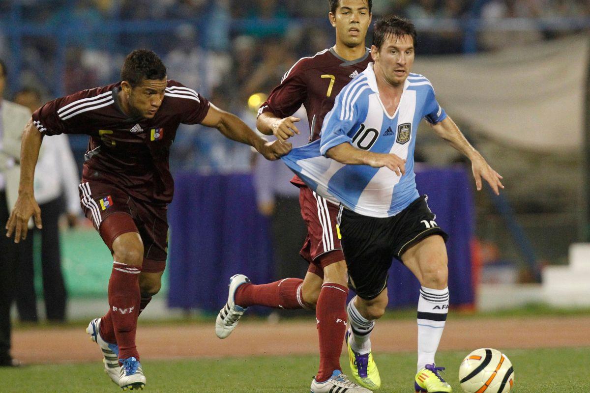 Venezuela's Agnel Flores (L) and Nicolas Fedor fight for the ball with Argentina's Lionel Messi (right) during their international friendly soccer match in Kolkata September 2, 2011.