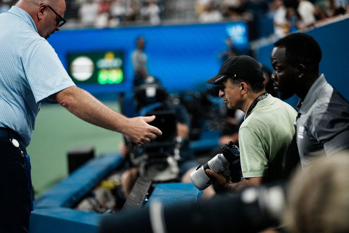 A staff member escorts a photographer out during the match between France's Benjamin Bonzi and Russia's Daniil Medvedev 