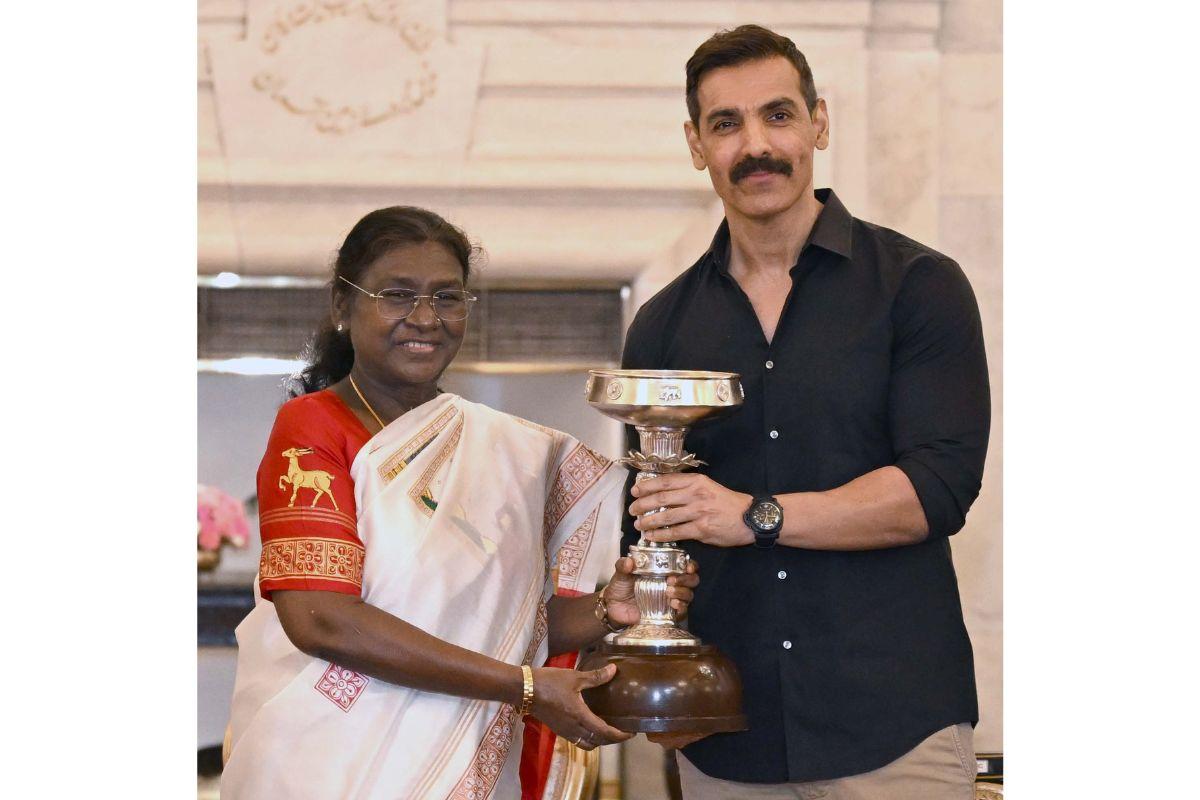 President Draupadi Murmu hands NEUFC'S owner John Abraham the President's Cup at a felicitation ceremony at the Rashtrapati Bhavan in New Delhi on Wednesday