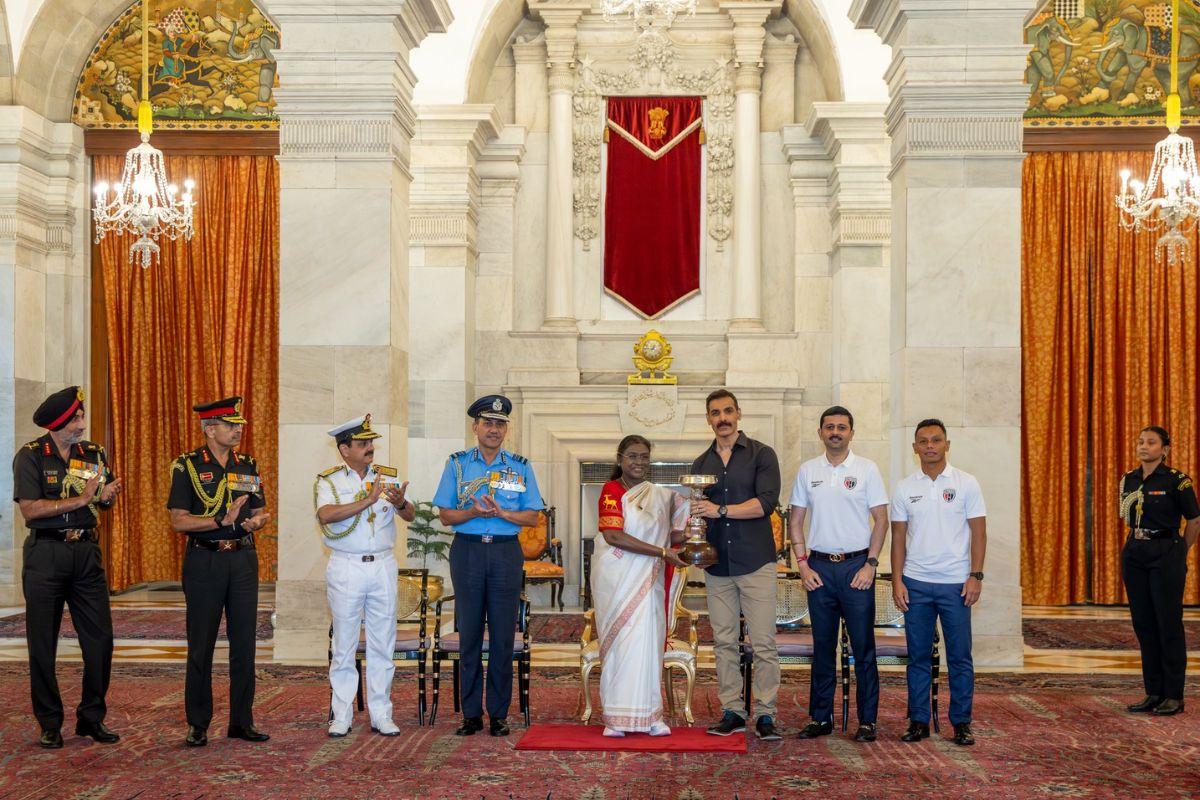 President Draupadi Murmu gives the trophy to NEUFC owner John Abraham in presence of dignitaries from the armed forces