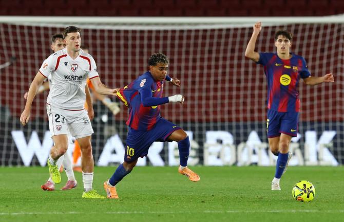 Barcelona's Lamine Yamal is checked by Osasuna's Abel Bretones as he breaks through.