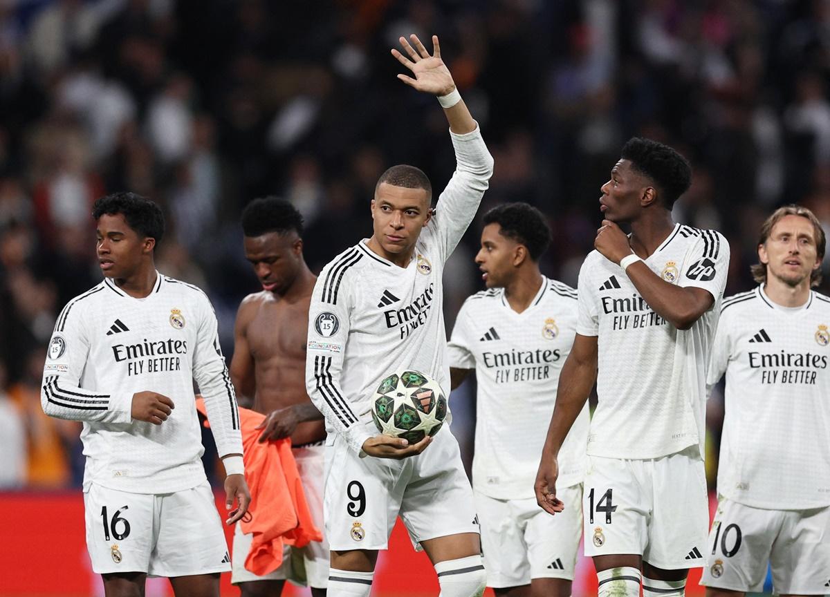 Kylian Mbappe celebrates with his Real Madrid teammates as he walks off the field with the ball after the match.