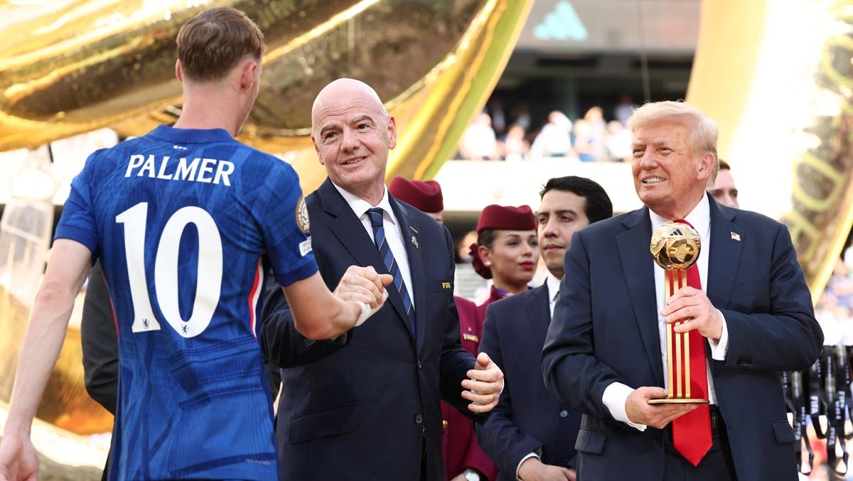 US President Donald Trump holds the Golden Ball trophy as Cole Palmer, Chelsea's 'Player of the Club World Cup' greets FIFA president Gianni Infantino.