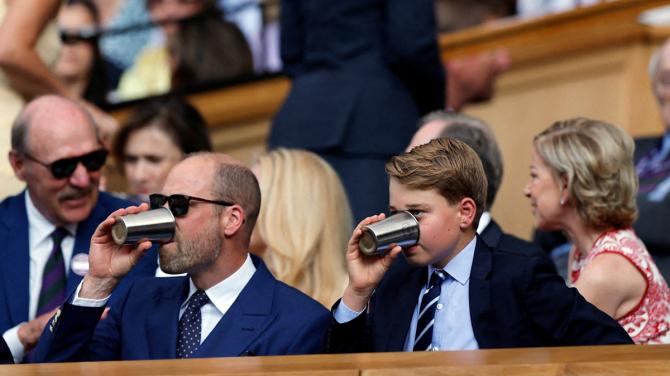 Britain's William, Prince of Wales and his son Prince George take a drink in the royal box