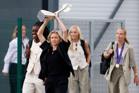 England's Leah Williamson holds the trophy next to Michelle Agyemang as they arrive at London Southend Airport on Monday, after winning the UEFA Women's Euro 2025