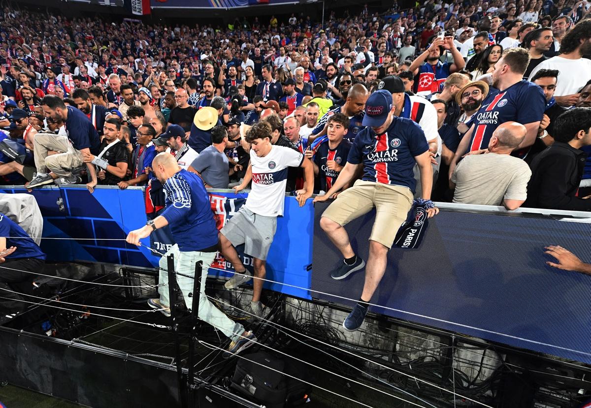 Paris St Germain fans climb down onto the pitch after the final whistle.