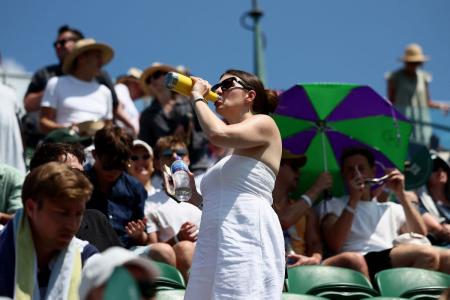 A spectator drinks water in the stands during the first round match between Russia's Daniil Medvedev and France's Benjamin Bonzi