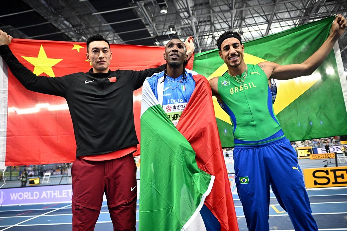 Italy's Andy Diaz Hernandez celebrates winning the men's Triple Jump alongside second-placed China's Yaming Zhu and third-placed Brazil's Almir Dos Santos.