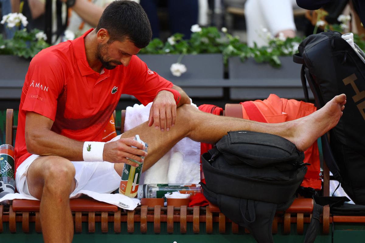Serbia's Novak Djokovic has a look at a blistered tow that was bothering him during his French open second round match against France's Corentin Moutet on Thursday