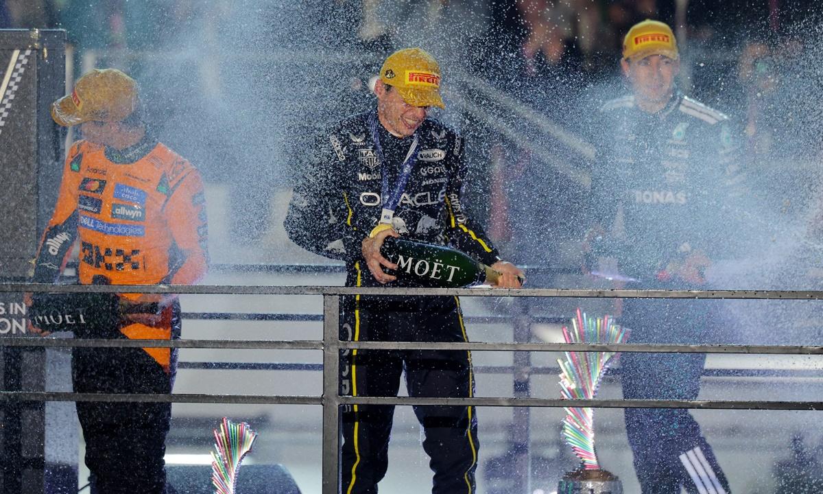 Max Verstappen celebrates on the podium along with second-placed McLaren's Lando Norris and third-placed George Russell of Mercedes.